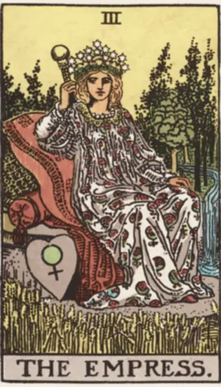 The Empress: a crowned figure resting on cushions in a field of ripe wheat, a sceptre in one hand, a heart-shaped shield beside her, and trees and falling water behind.